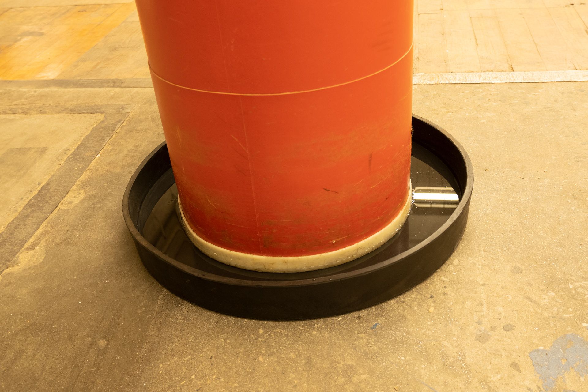 Round Killarney Metals rubber drip pan containing spill from Drum